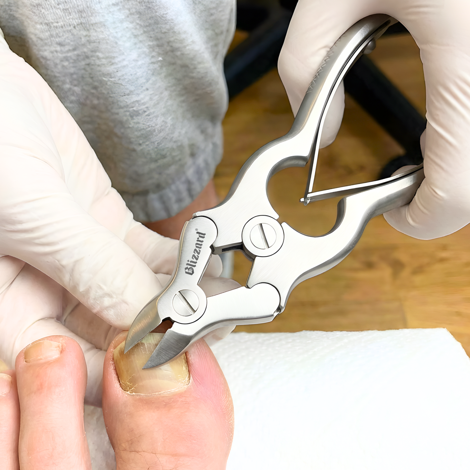 Person using a nail clipper on a finger with gloves on